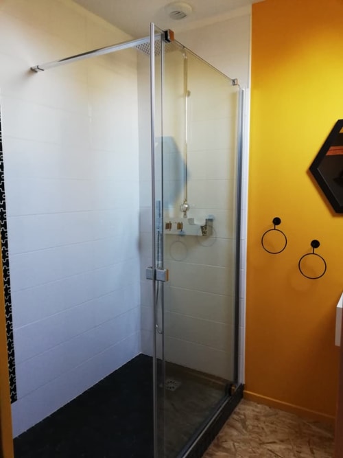 Douche en verre moderne aux finitions noires et murs en carrelage blanc à la chambre Chez Morine et Jeanne, La Cour d'Hortense