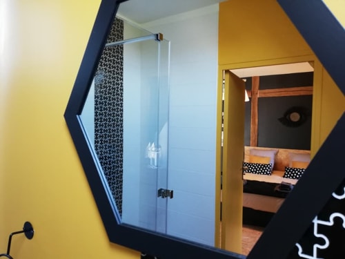 Miroir hexagonal reflétant la salle de bain avec douche en verre du gîte La Cour d'Hortense à Sailly-Flibeaucourt, France
