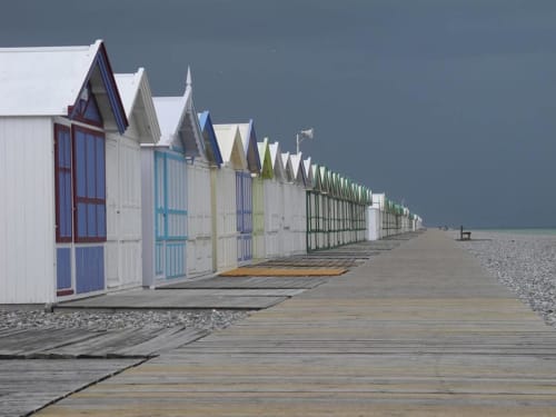 Des cabines colorées bordent la promenade en bois de La Cour d'Hortense à Sailly-Flibeaucourt, France, sous un ciel dramatique