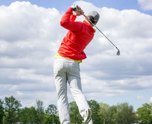 Golfeur en veste rouge en plein swing au golf de Concarneau près du Petit Manoir de Kériolet