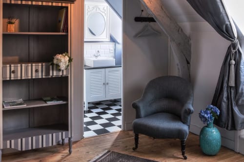 Élégant coin salon dans La chambre Delphine au Petit Manoir de Kériolet, Concarneau avec fauteuil sombre, bibliothèque et