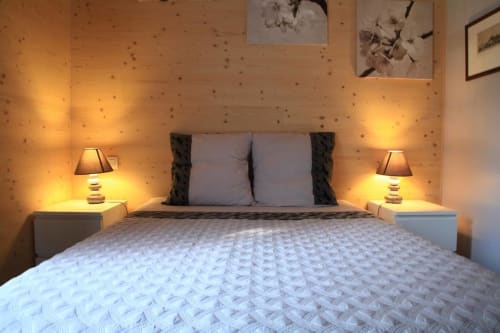 Acogedora habitación doble en Maison Addama en Neyron con iluminación cálida, paredes de madera y vista al jardín