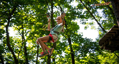 Child on zipline through forest canopy at Maison Addama adventure activity in Neyron, France