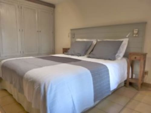 Spacious bedroom at Villa Thébaïde B&B with queen bed, gray headboard, white bedding, wardrobe, nightstand, and terrace
