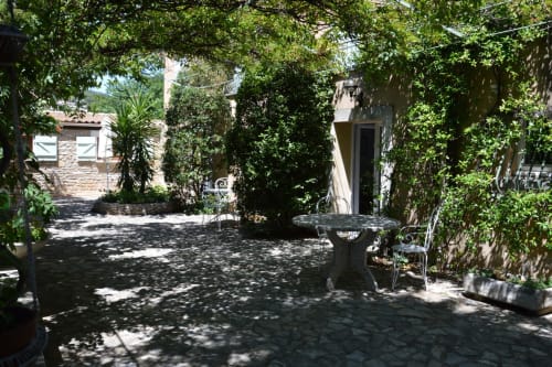 Üppiger Innenhofgarten der Villa Thébaïde in Laudun L'Ardoise mit efeubedeckten Mauern und Steinensitzbereich