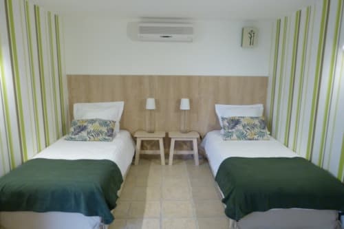 Twin beds with green striped curtains in the Bambou room at Villa Thébaïde, Laudun L'Ardoise