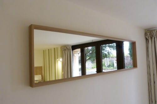 Modern wooden-framed mirror reflecting garden view in Bambou room at Villa Thébaïde, Laudun L'Ardoise