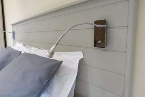 Modern bedside with flexible reading light and wall-mounted brown fixture in Cérise room at Villa Thébaïde