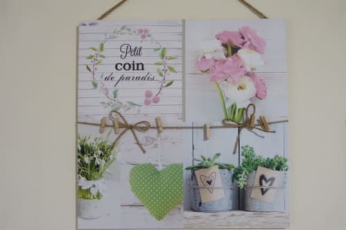 Decorative garden wall hanging at Villa Thébaïde with flowers, potted plants, and 'Petit coin de paradis' text