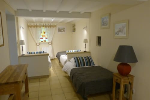 Spacious bedroom at Villa Thébaïde in Laudun with twin beds, striped pillows, wooden furnishings, and garden views from
