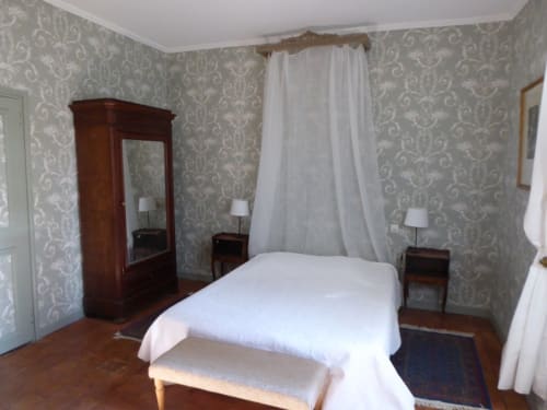 Camera storica presso il Domaine de Lamartine con carta da parati damascata, guardaroba in legno, biancheria bianca e vista sul giardino