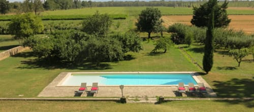 Piscina rettangolare con lettini sulla terrazza del Domaine de Lamartine, Pont-Saint-Esprit, circondata da prati verdi e cipressi