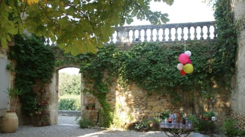Ivy-covered stone courtyard at Domaine de Lamartine B&B in Pont-Saint-Esprit with decorative balloons and terrace balustrade
