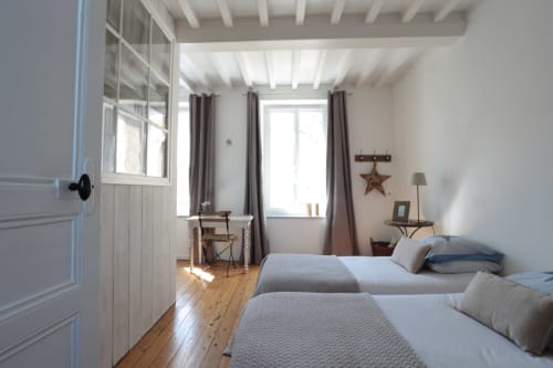 Chambre lumineuse avec deux lits jumeaux, poutres apparentes et vue sur le port à la maison d'hôtes Les Filles du Bord de Mer