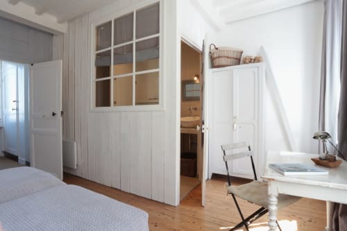 Chambre lumineuse à La Maison sur le Quai avec murs lambrisés blancs, parquet et salle de bain avec vue sur mer aux Filles
