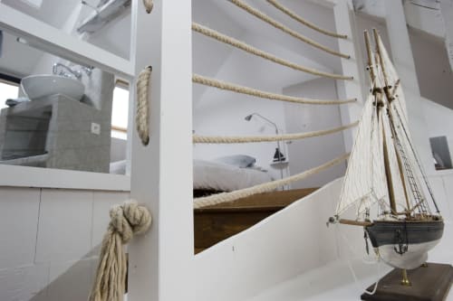 Chambre côtière avec détails marins, maquette de voilier et vue sur le port par la fenêtre aux Filles du Bord de