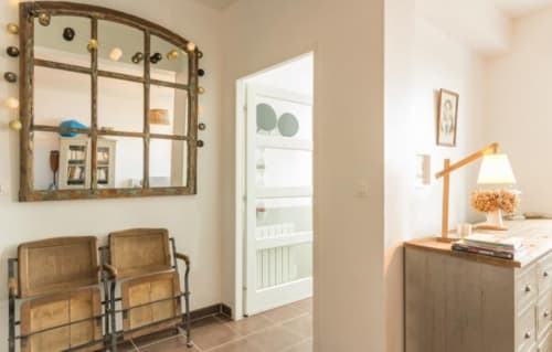 Chambre chaleureuse à Les Filles du Bord de Mer, Port-en-Bessin, avec mobilier en bois, miroir rustique et éclairage chaleureux