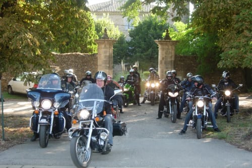 Motorcycle group gathering at Domaine de Lamartine in Pont-Saint-Esprit with headlights on near stone gates