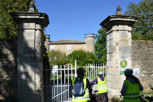 Ciclisti al cancello bianco d'ingresso del Domaine de Lamartine, uno château in pietra a Pont-Saint-Esprit, Francia