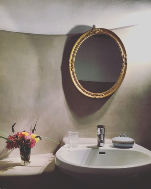 Elegant bathroom sink with gold-framed oval mirror and fresh flowers at Domaine de Lamartine, Pont-Saint-Esprit