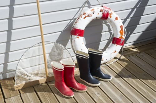 Décor marin aux Filles du Bord de Mer : bouée de sauvetage, filet de pêche et bottes colorées sur pont en bois