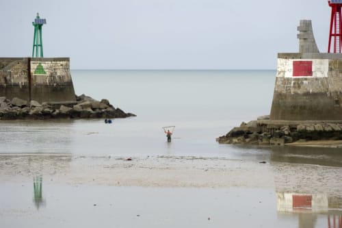 Entrée du port de Port-en-Bessin avec deux phares et digues en pierre à marée basse