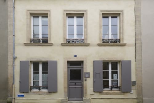Classic French building facade in Port-en-Bessin with shuttered windows and central entrance door