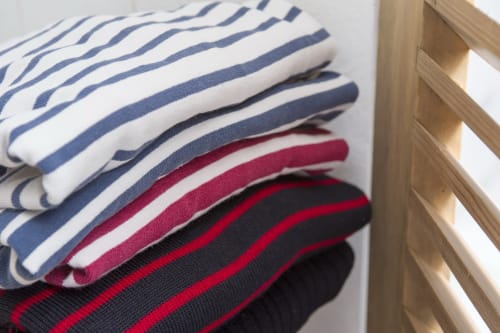 Serviettes rayées soigneusement pliées en bleu marine, rouge et noir à l'hôtel Les Filles du Bord de Mer