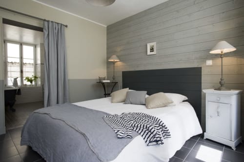 Modern bedroom at Les Filles du Bord de Mer hotel in Port-en-Bessin with grey wood accent wall and white bedding