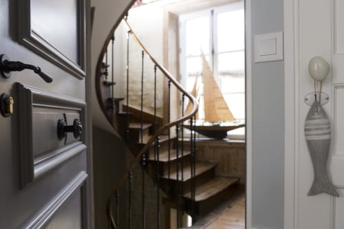 Modern spiral staircase with wooden handrail and glass panels at Les Filles du Bord de Mer hotel, Port-en-Bessin