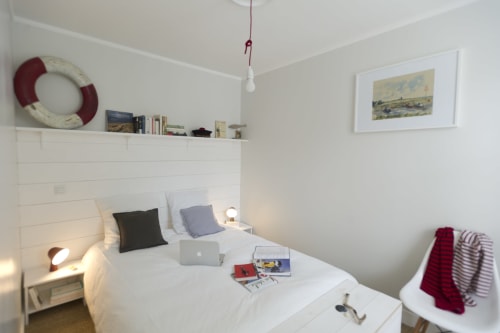 Bright, minimalist bedroom at Les Filles du Bord de Mer with white shiplap, nautical décor, and modern amenities in