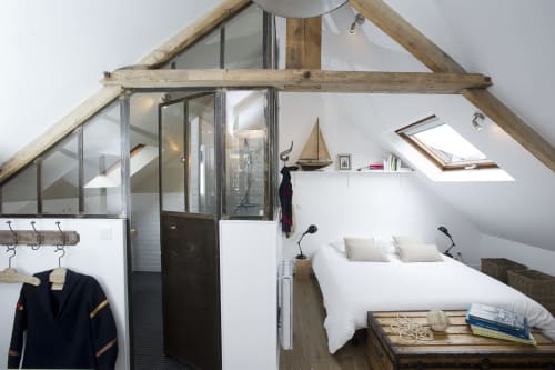 Modern attic bedroom with exposed wooden beams, white linens, skylight, and ensuite bathroom at Les Filles du Bord de Mer,
