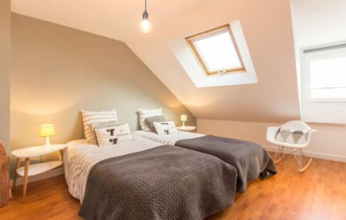 Bright attic bedroom at Les Filles du Bord de Mer with skylights, wooden floors, and modern furnishings in