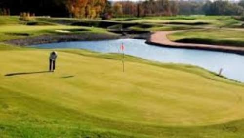 Golfer putting on scenic green at Maison Addama, a bed and breakfast in Neyron, France, with water hazard and autumn trees