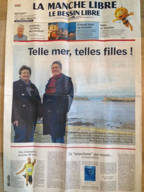 Zwei Frauen stehen am Meer in Port-en-Bessin und werben für das Hotel Les Filles du Bord de Mer