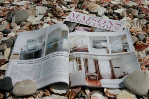 Magazinseite mit den Innenräumen des Hotels Les Filles du Bord de Mer an einem Kieselstrand mit Muscheln