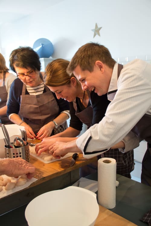 Cours de cuisine en groupe à l'hôtel Les Filles du Bord de Mer à Port-en-Bessin, clients apprenant ensemble les techniques culinaires