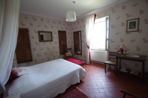Camera spaziosa al Domaine de Lamartine con carta da parati floreale, letto bianco, mobili in legno e ampia finestra