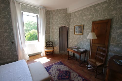 Historic bedroom in La Tour at Domaine de Lamartine with period wallpaper, wooden furniture, and garden views