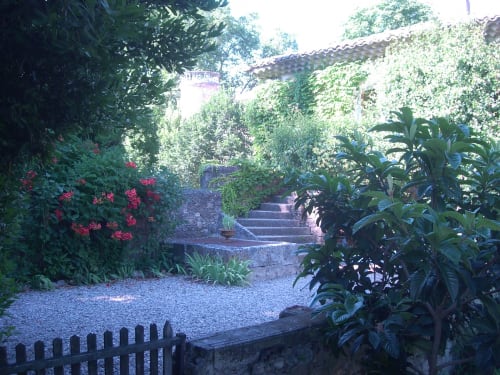 Lush garden pathway at Domaine de Lamartine cottage in Pont-Saint-Esprit with blooming flowers and ivy-covered walls