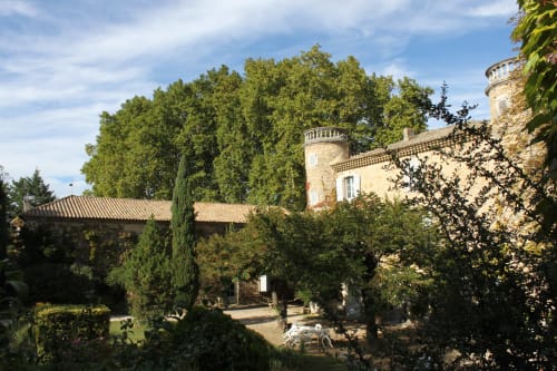 Medieval stone castle tower surrounded by lush garden trees at Domaine de Lamartine, Pont-Saint-Esprit