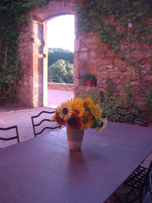 Bouquet di girasoli su tavolo al Domaine de Lamartine, arco in pietra rustica con vista sulla campagna di Pont-Saint-Esprit