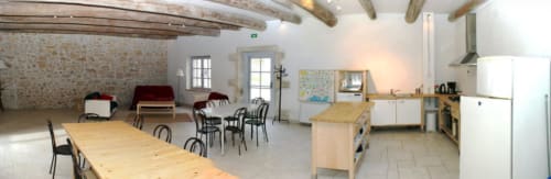 Bright cottage dining area at Domaine de Lamartine with wooden tables, kitchen, exposed beams and garden view