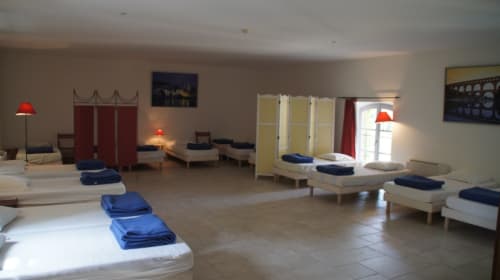 Dormitory-style bedroom at Domaine de Lamartine in Pont-Saint-Esprit with multiple beds, blue linens, red lamps, and shared
