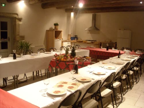 Elegant dining room at Domaine de Lamartine with long tables, red table runners, place settings, and open kitchen in