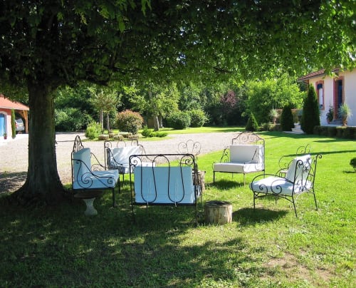 Salon extérieur du Domaine de La Serita avec mobilier en fer forgé sous les arbres à Jozé, France