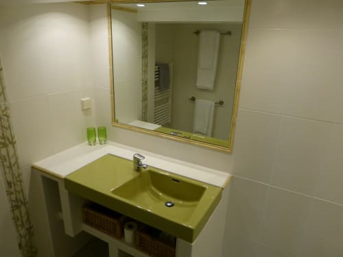 Modern bathroom with green sink and white countertop in Villa Thébaïde guesthouse room, featuring large mirror and tiled