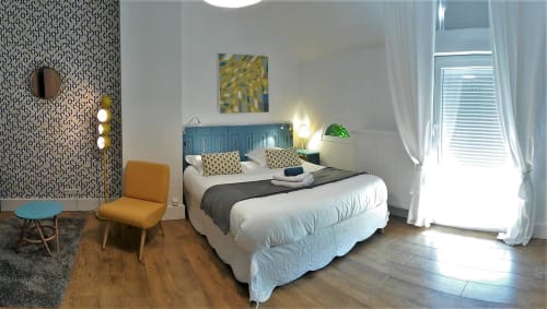 Chambre vintage de la villa Domaine de La Serita à Joze avec tête de lit bleue, literie blanche, papier peint à motifs et coin salon