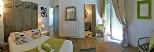 Chambre lumineuse à la Domaine de La Serita avec coussins colorés, armoire en bois, miroir à cadre vert et équipements modernes