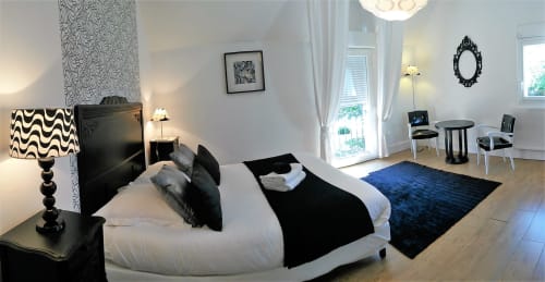 Chambre moderne au Domaine de La Serita à Joze avec lit blanc, accents noirs, mobilier élégant et coin détente